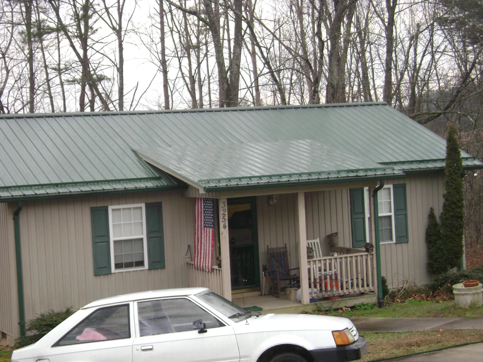 Green metal roof and front porch on a tan sided cottage in Josephine