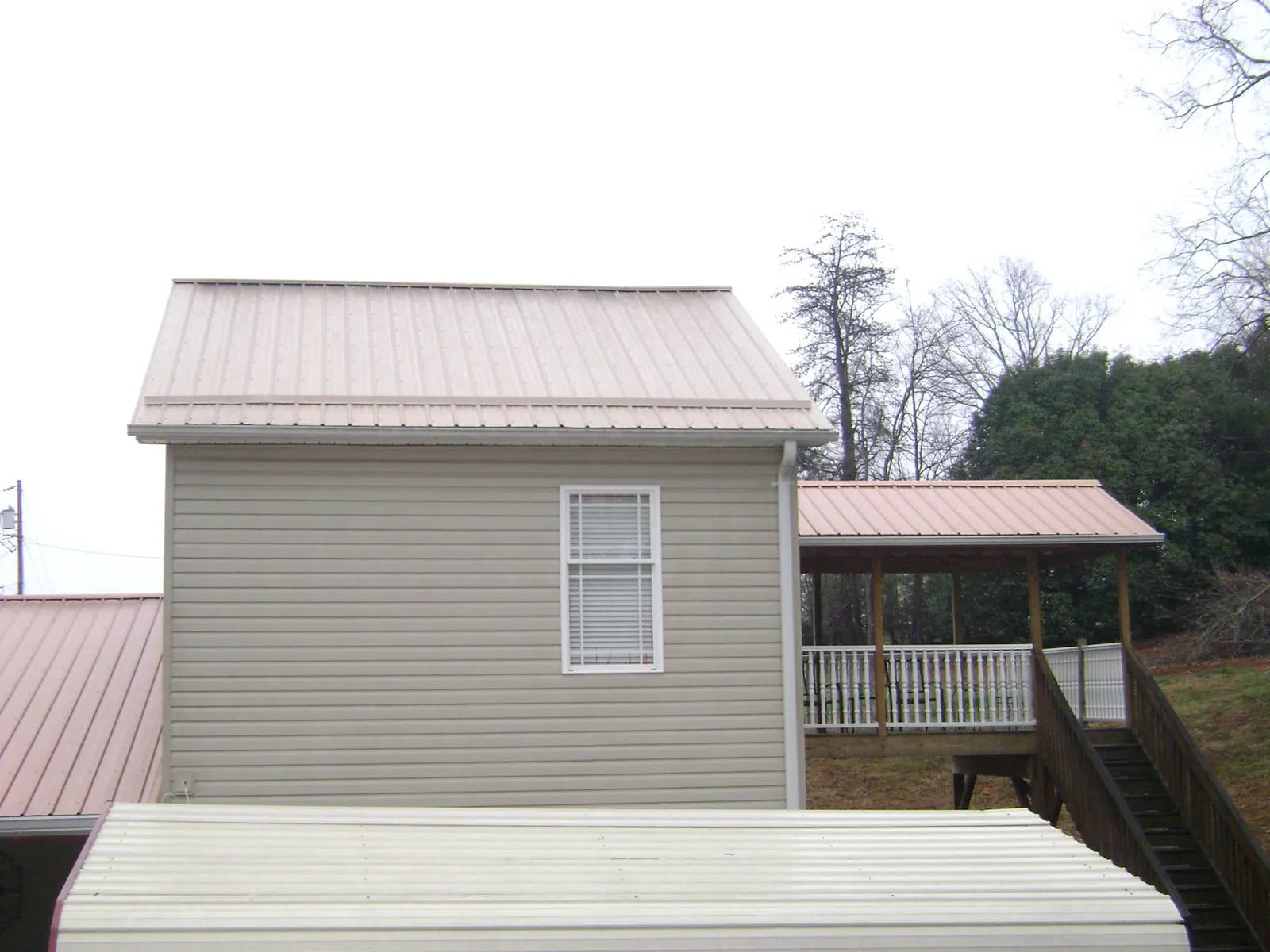 Tan metal roofs on a two story addition and attached porch, from a Roof Replacement job in Josephine