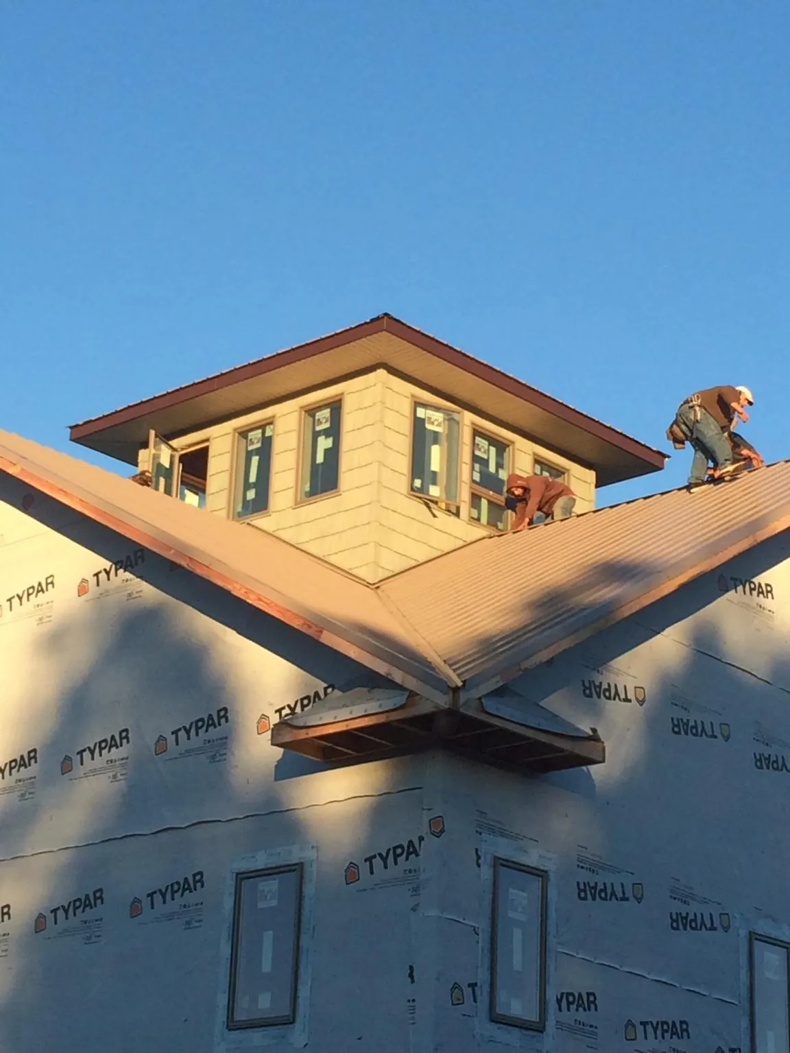 Roofers working around a rooftop cupola on a new metal roof at sunset — Roof Waterproofing in Josephine by Roofing Brothers